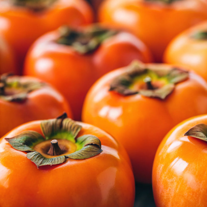 Close-up of several bright orange persimmons with green stems.